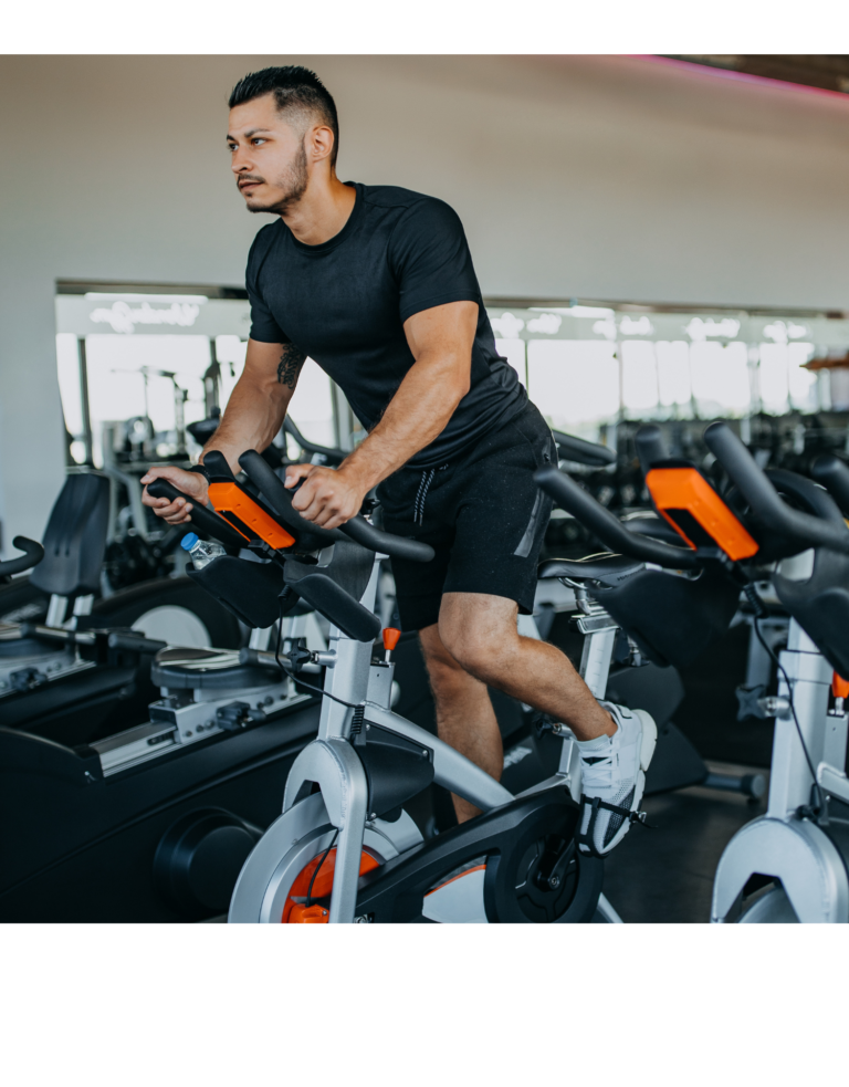 Homem pedalando uma Bike Spinning dentro da academia