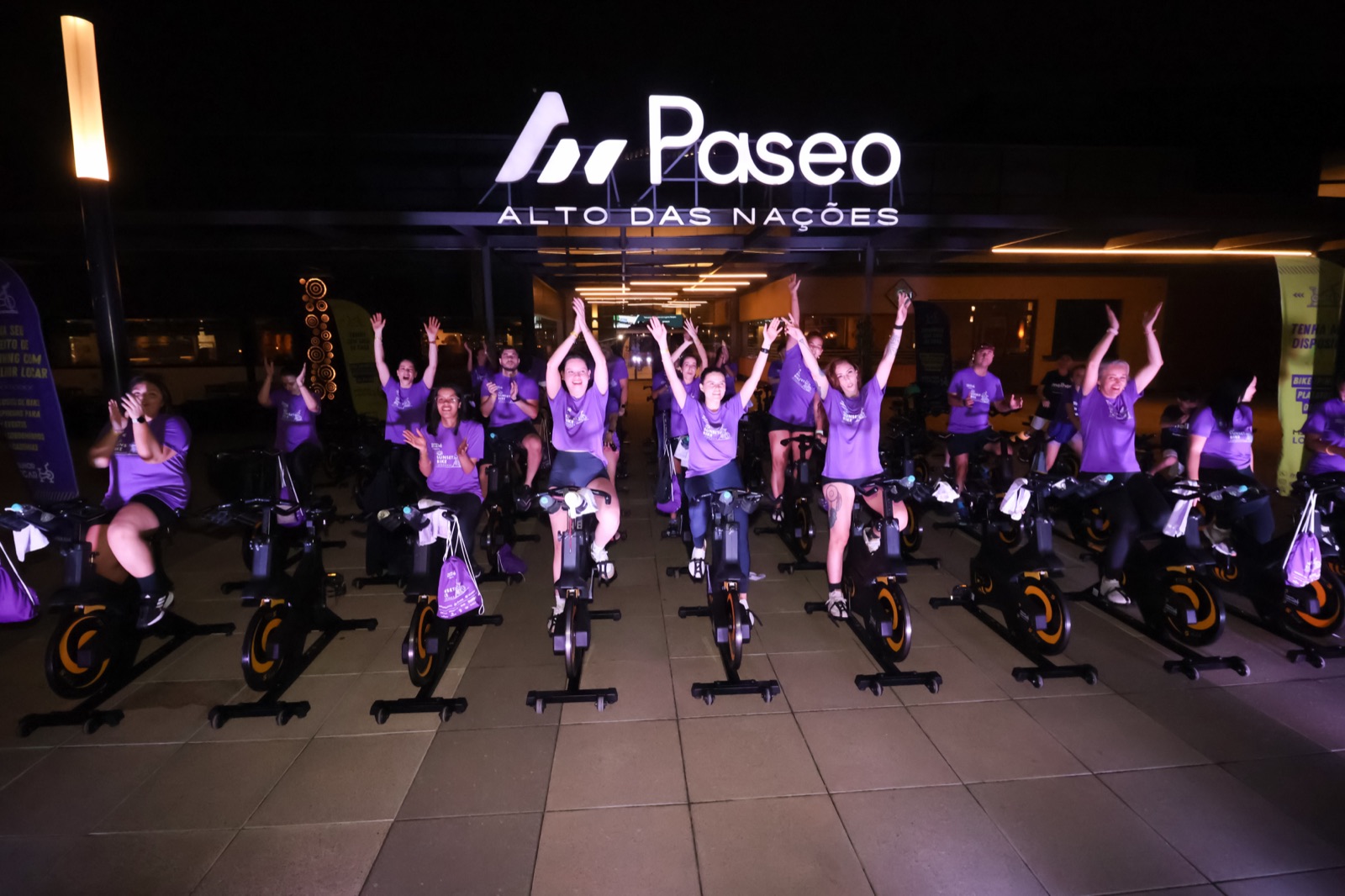 Participantes celebrando em evento noturno de spinning da Melhor Locar