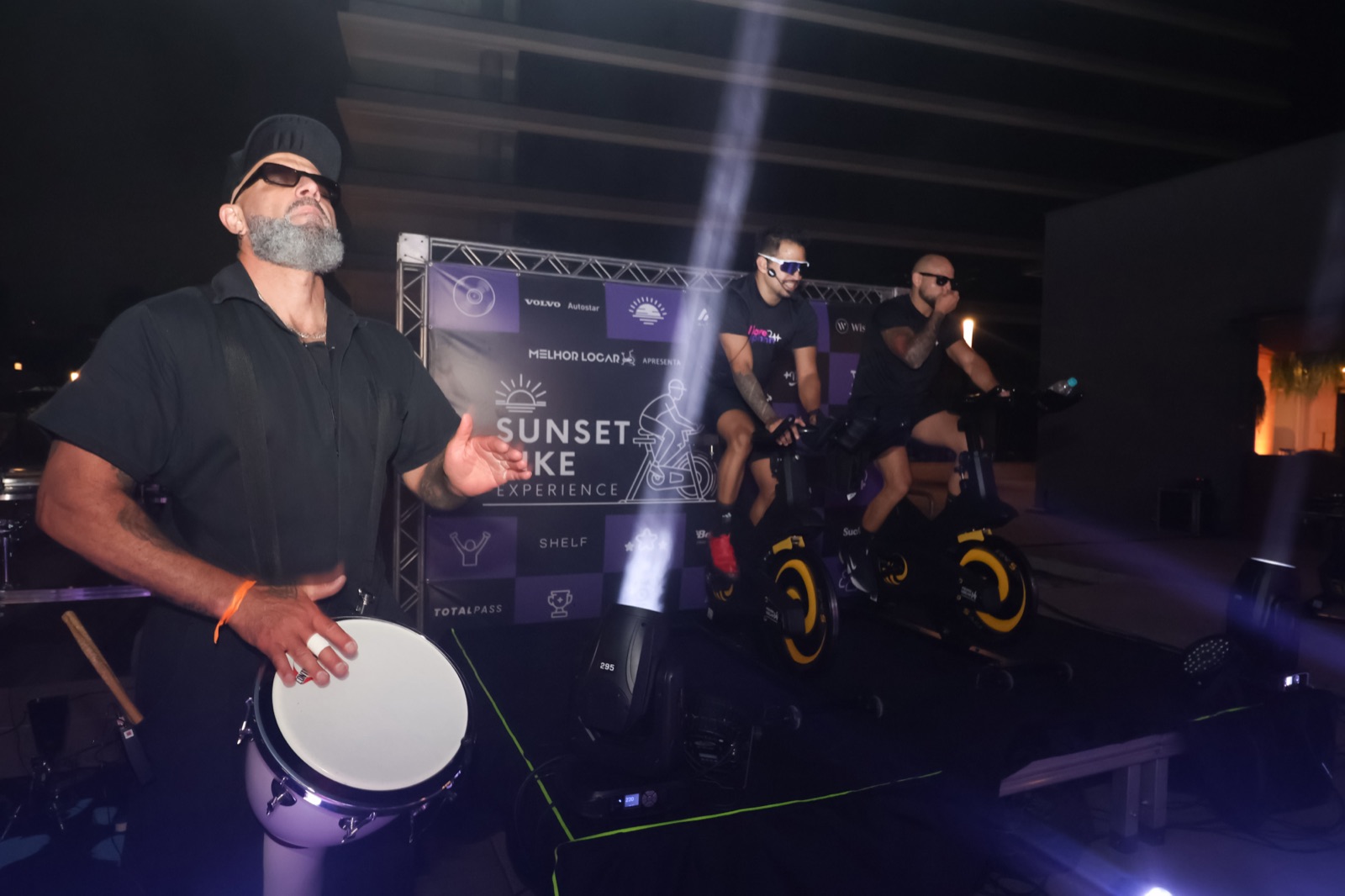 Palco com percussão ao vivo e instrutores no Sunset Bike Experience